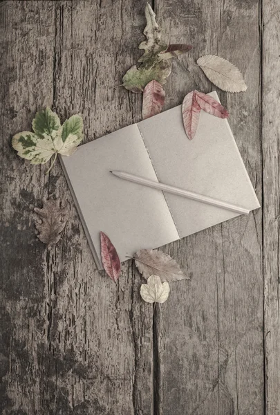 Cuaderno sobre mesa de madera decorado con hojas de otoño — Foto de Stock