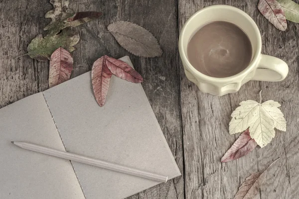 Café y cuaderno en la mesa decorado con hojas secas de otoño — Foto de Stock