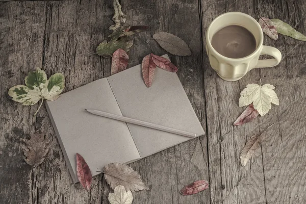 Café y cuaderno en la mesa decorado con hojas secas de otoño — Foto de Stock