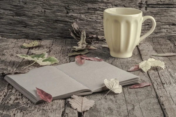 Café y cuaderno en la mesa decorado con hojas secas de otoño — Foto de Stock