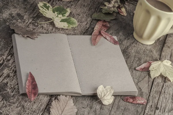 Café y cuaderno en la mesa decorado con hojas secas de otoño — Foto de Stock