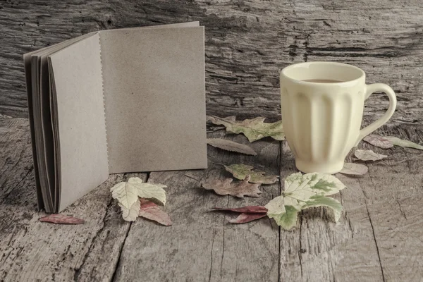 Coffee and notebook on table decorated with dried autumn leaves — Stock Photo, Image