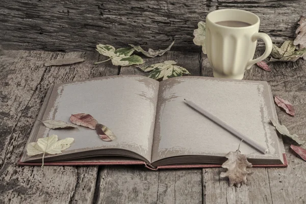 Café y cuaderno en la mesa decorado con hojas secas de otoño — Foto de Stock