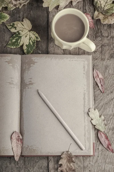 Café y cuaderno en la mesa decorado con hojas secas de otoño — Foto de Stock