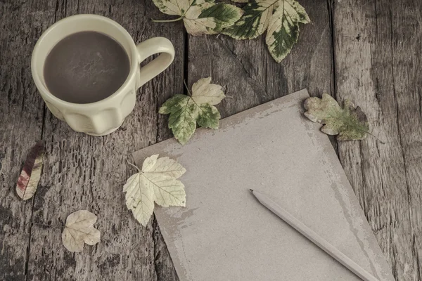 Café y cuaderno en la mesa decorado con hojas secas de otoño — Foto de Stock