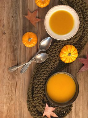 Kurumuş sonbahar yapraklarıyla süslenmiş ahşap bir masada kabak çorbaları.