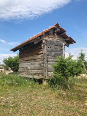 Baharın güneşli bir gününde kırsal bir alanda küçük bir ahşap kulübe.