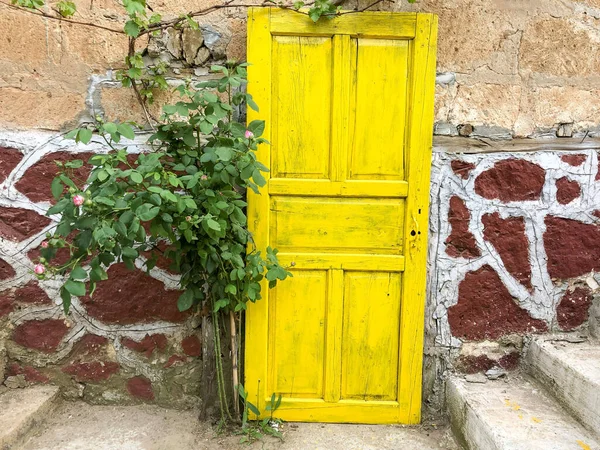 a yellow painted wooden door on the wall of an old house