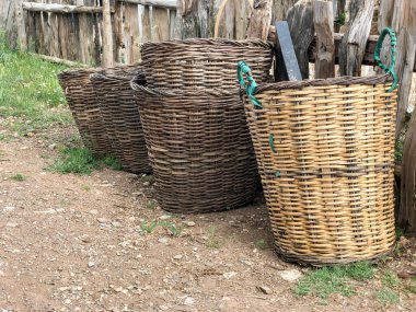 Boş hasır sepetler köyün ahşap çitlerinin önünde dizilmişti.