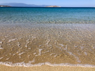 Yazın kumlu bir sahilde sakin bir denizin yumuşak dalgaları