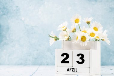 Nisan ayı için beyaz küp takvimi mavi arkaplan üzerinde papatya çiçekleri ile fotokopi alanı ile süslenmiş