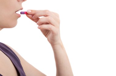 Genç bir kadın beyaz arka plan üzerinde fotokopi alanı ile hap alıyor.