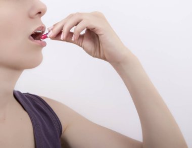 Genç bir kadın beyaz arka plan üzerinde fotokopi alanı ile hap alıyor.