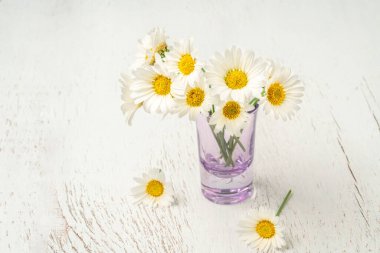 Tahta masadaki vazoda papatya çiçekleri fotokopi alanı var.