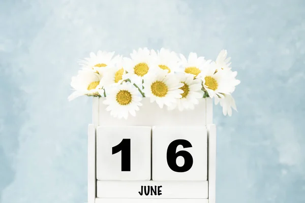 白いキューブカレンダー6月のためにデイジーの花の上に青の背景にコピースペース — ストック写真
