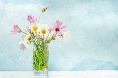 Yumuşak mavi arkaplan üzerine renkli bahar çiçekleri.