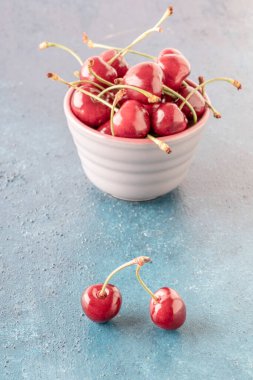 Olgun ve taze kiraz meyveleri mavi arka planda bir kasede fotokopi alanı ile