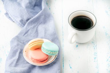 Renkli badem kurabiyeleri ve bir fincan kahve fotokopi alanı olan ahşap masa üzerinde.