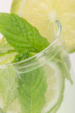 Limon dilimleri ve nane yapraklı kokteyl bardağını kapat.