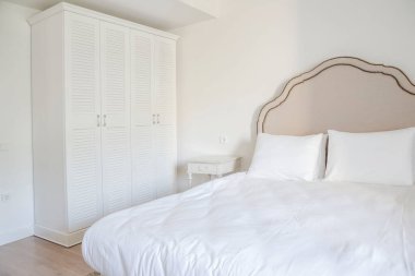 Yatak odasının içinde iki kişilik bir yatak odası ve gardırop.