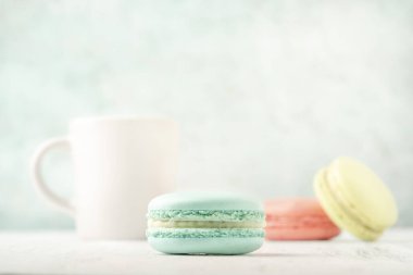 Renkli badem kurabiyeleri ve bir fincan kahve yeşil arka planda fotokopi alanı olan bir masada.