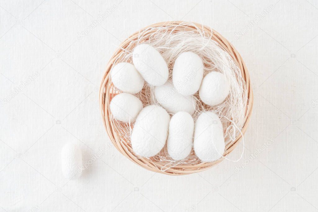 closeup white silkworm cocoons shells, source of silk fabric in the basket on table with copy space