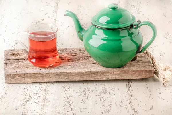 glass of Turkish tea and vintage enemaled teapot on table