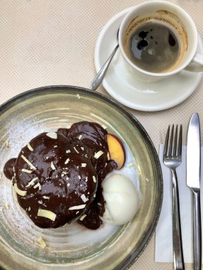 Bir fincan kahve ve çikolatalı kek, masada dondurma.