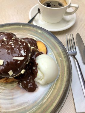 Bir fincan kahve ve çikolatalı kek, masada dondurma.