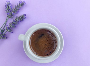 Eflatun çiçeklerle süslenmiş mor arka planda bir fincan Türk kahvesi.