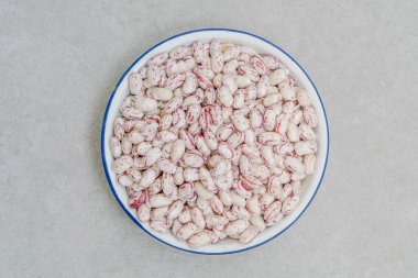 Masanın üzerinde bir kase çiğ fasulye var.