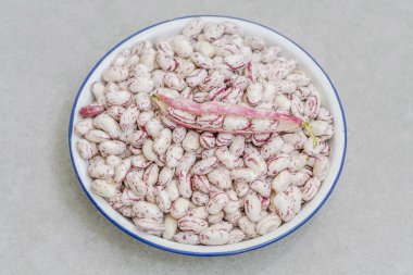 Masanın üzerinde bir kase çiğ fasulye var.