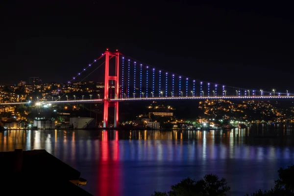 İstanbul, Türkiye 'de geceleyin denizi yansıtan ışıklı Boğaz Köprüsü