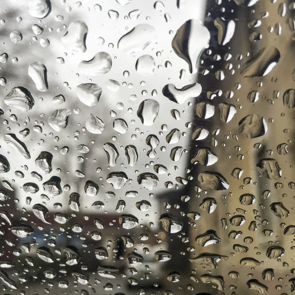 Gotas de lluvia en la ventana sobre edificios — Foto de Stock