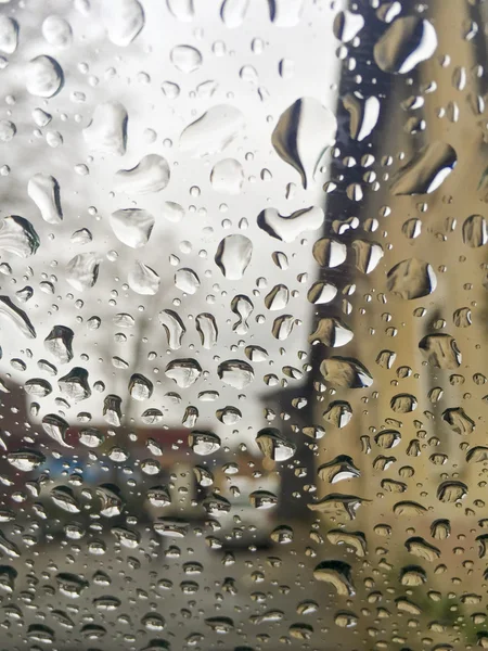 Regentropfen auf Fenster über Gebäuden — Stockfoto