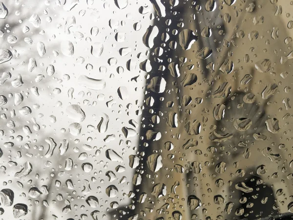 Regentropfen auf Fenster über Gebäuden — Stockfoto