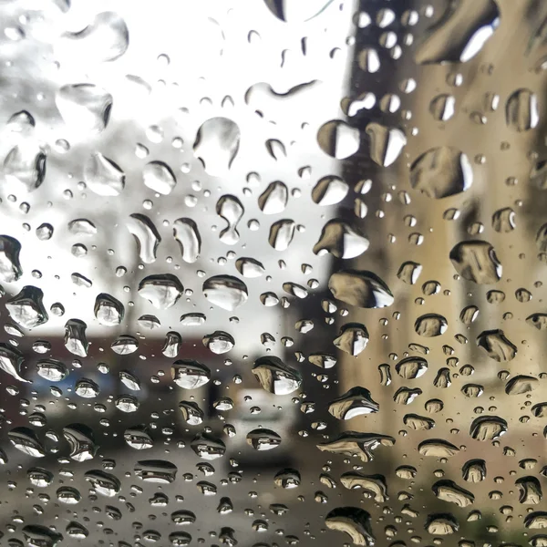 Regentropfen auf Fenster über Gebäuden — Stockfoto