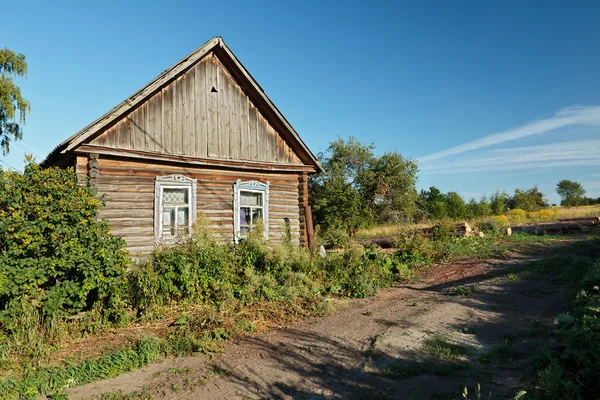 Деревянный дом в российской сельской местности рядом с непокрытой дорогой — стоковое фото
