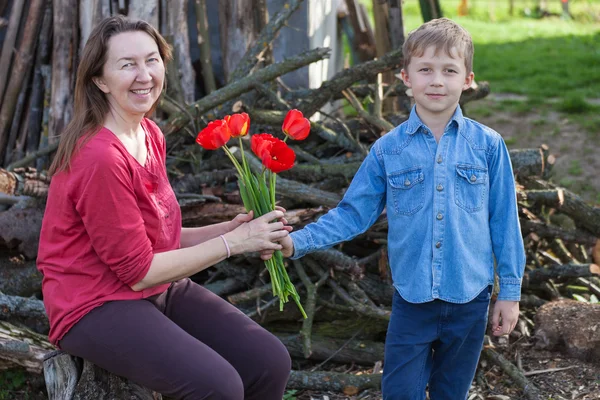 Chłopak daje tulipany babki — Zdjęcie stockowe