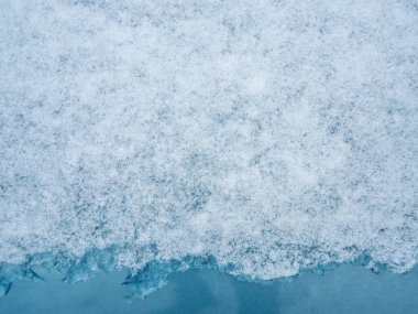 Mavi metal yüzey kar ve buzla kaplı. Yakın plan, soyut arkaplan, doğal doku.