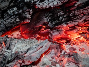 Soyut arkaplan olarak odunların yakın plan yakılması. Yanan odun ateşinin sıcak közleri. Yakacak odun ızgarada yanıyor. Doku ateş közleri. Alevli ateş