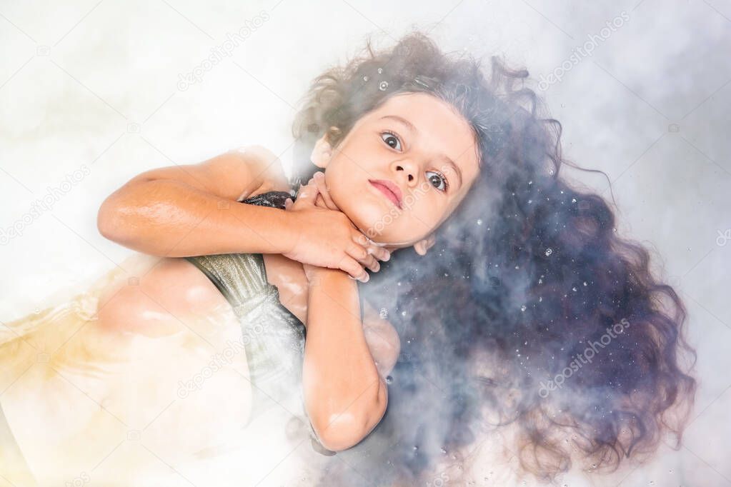Girl with gorgeous long hair, lying in the water, hugs her neck with her hands and looks through the fog, Halloween concept