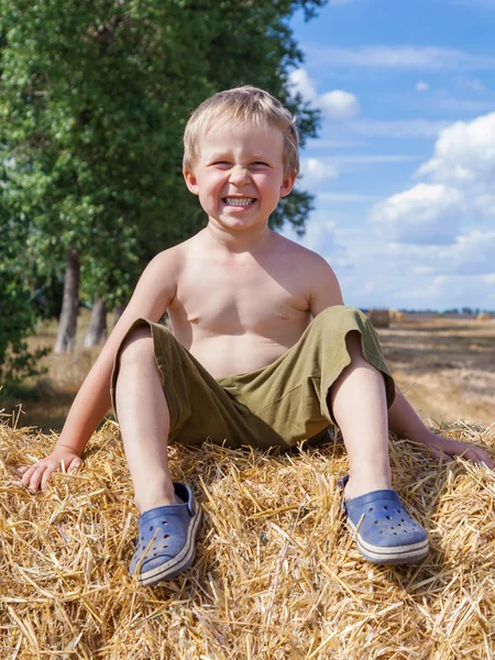 Chlapec seděl na balíku slámy — Stock fotografie