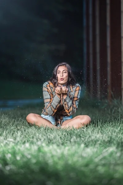 Adolescente chica caucásica soplando brillo de sus manos sentado —  Fotos de Stock