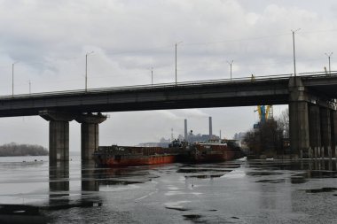 Nehir ve köprü. Köprünün altında gemiler var. Buz ve gemilerden oluşan bir manzara. Nehirdeki beton köprü. port ve gemiler