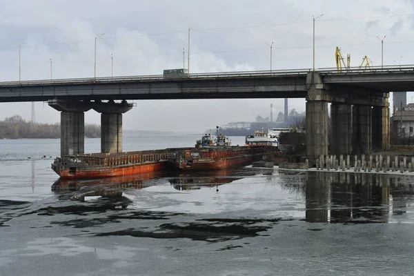 river and bridge. ships under the bridge. landscape with ice and ships. concrete bridge on the river. port and ships