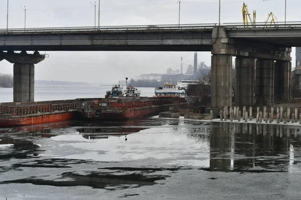 river and bridge. ships under the bridge. landscape with ice and ships. concrete bridge on the river. port and ships