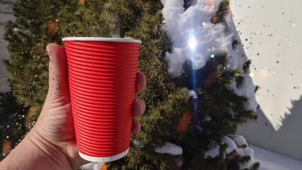 冬の曇りの日には コーヒーのホットカップが窓辺に立っています 背景に雪が揺れると木々の枝がぼやけて シームレスなループアニメーションの動きが背景をレンダリングします 自然界のお茶 — ストック動画