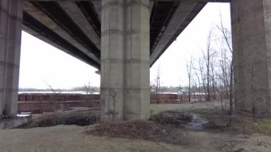 Büyük köprünün altında. Güçlü demir köprü yapısı, aşağıdan görünüyor. Köprünün altından bir nehir akıyor. Bakış açısı. Şehir mimarisi. Şafak vakti köprüde. Köprülerin inşası.