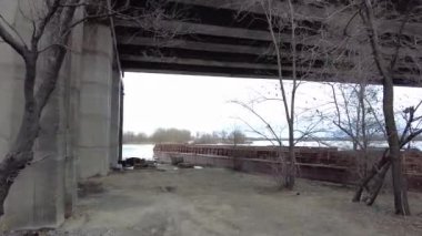 Büyük köprünün altında. Güçlü demir köprü yapısı, aşağıdan görünüyor. Köprünün altından bir nehir akıyor. Bakış açısı. Şehir mimarisi. Şafak vakti köprüde. Köprülerin inşası.